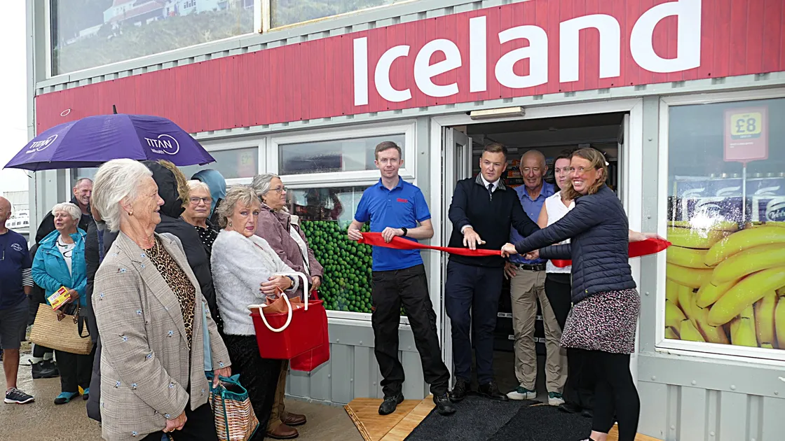 Beth Chapman, director of Bell & Co, cuts the ribbon to declare the new Alderney Iceland store open, watched by staff and Alliance Group chief operating officer Keiran Poole, second left behind the ribbon, and a queue of new customers. 			 	 (Picture by David Nash)