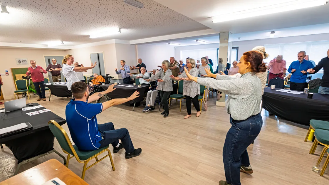 Michelle Young from the Guernsey Therapy Group's neuro outpatient physio team offering some key exercises at Parkinson’s Guernsey’s fifth anniversary celebrations