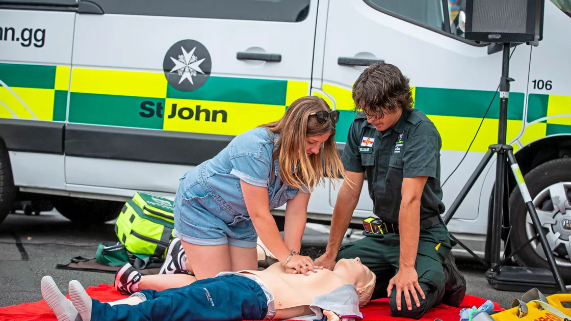 Jade Stranger is given a lesson in CPR by St John crew member William Frankland. Inset, the queue to board the Flying Christine. (Pictures by Peter Frankland, 33377999)