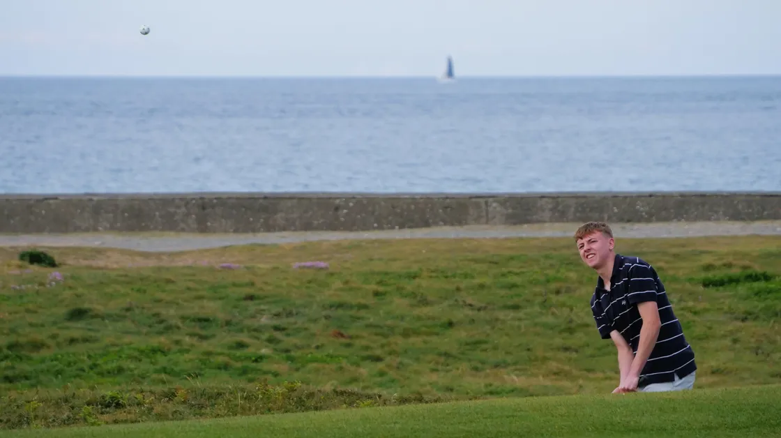 Kieran Marley playing a chip shot from the right-hand side of the 15th green.