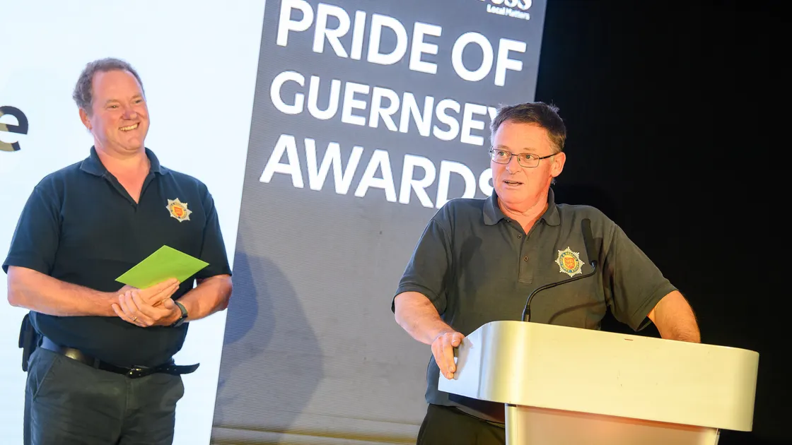 Watched by brother and fellow firefighter Simon Adams, Sark Fire & Rescue Service’s chief fire officer Kevin Adams accepts the Emergency Hero of the Year award at the 2026 Pride of Guernsey Awards on Saturday. 	