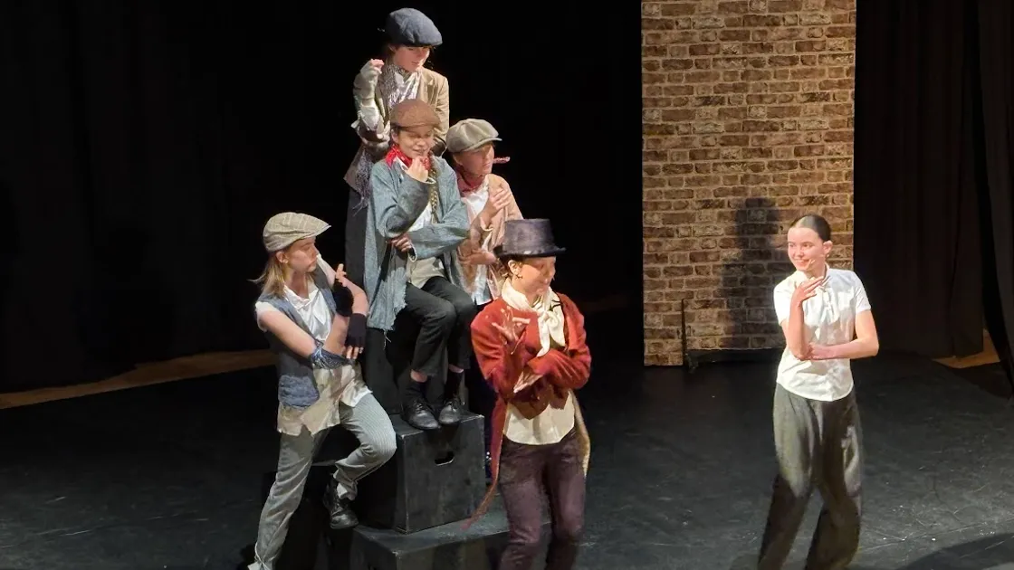 Oliver (played by Chloe Toumine, right) meets the top-hatted Artful Dodger (Peyton Snell) and his fellow pickpockets