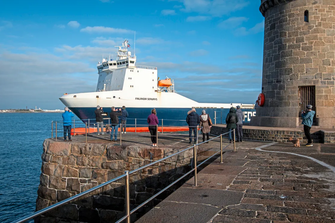 The DFDS Finlandia Seaways, with the Ports of Jersey tug Duchess accompanying her, approaches St Peter Port Harbour watched by a number of people.  (32808120)
