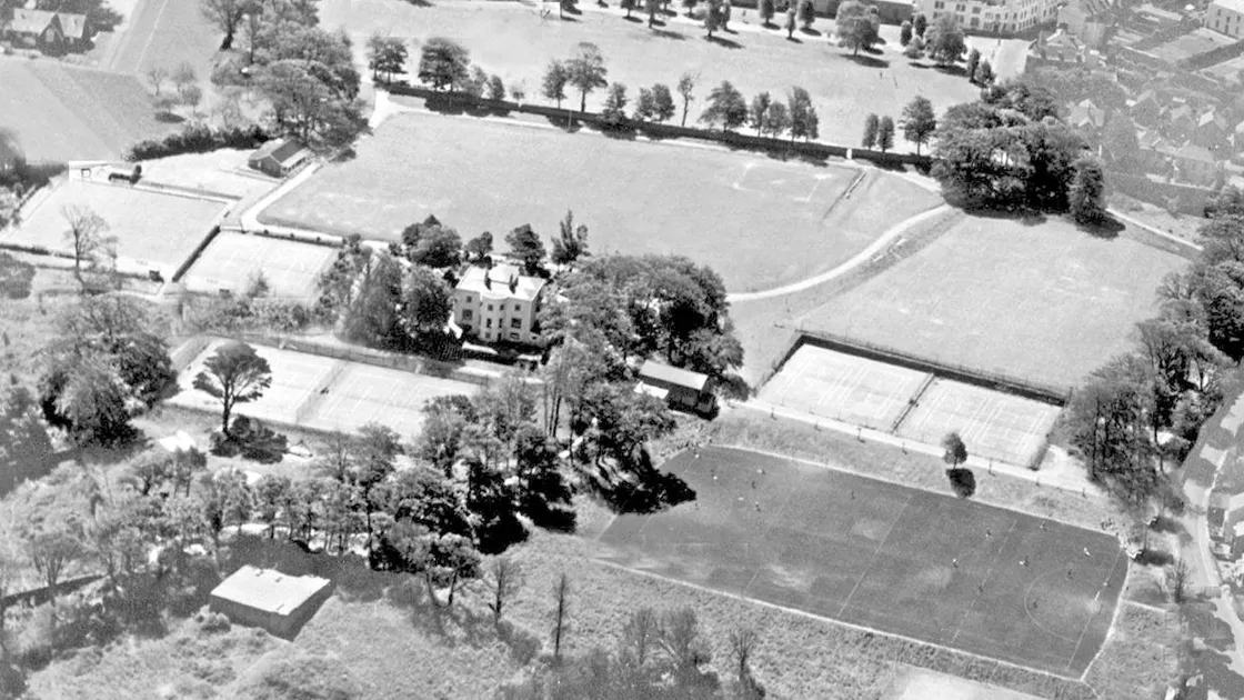 Beau Sejour as seen from the air in the mid-1950s The image shows 10 tennis courts in existence, the bowls green on the far left and the large multi-purpose hard surface in the foreground. At the heart of the image is the old Beau Sejour house
