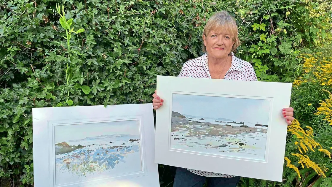 Canda Atkinson with two of late husband's watercolours of the Bailiwick, a view of Herm with Paradis in the foreground and a painting of Bordeaux Harbour . (33602230)