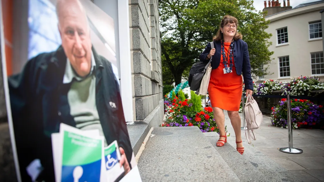 President of Employment & Social Security Michelle Le Clerc arriving at the Royal Court yesterday. The portrait left is a photograph of long time disability campaigner the late Dave Purdy. (Picture By Peter Frankland, 28476405)