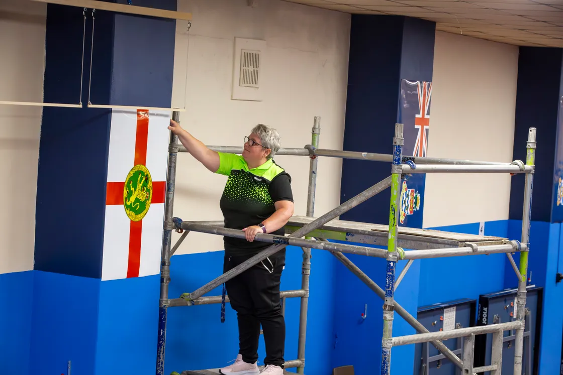Guernsey table tennis development officer Becks O'Keefe putting up the flags of visiting islands ahead of the Island Games competition starting on Sunday. (Picture by Luke Le Prevost, 32267903)