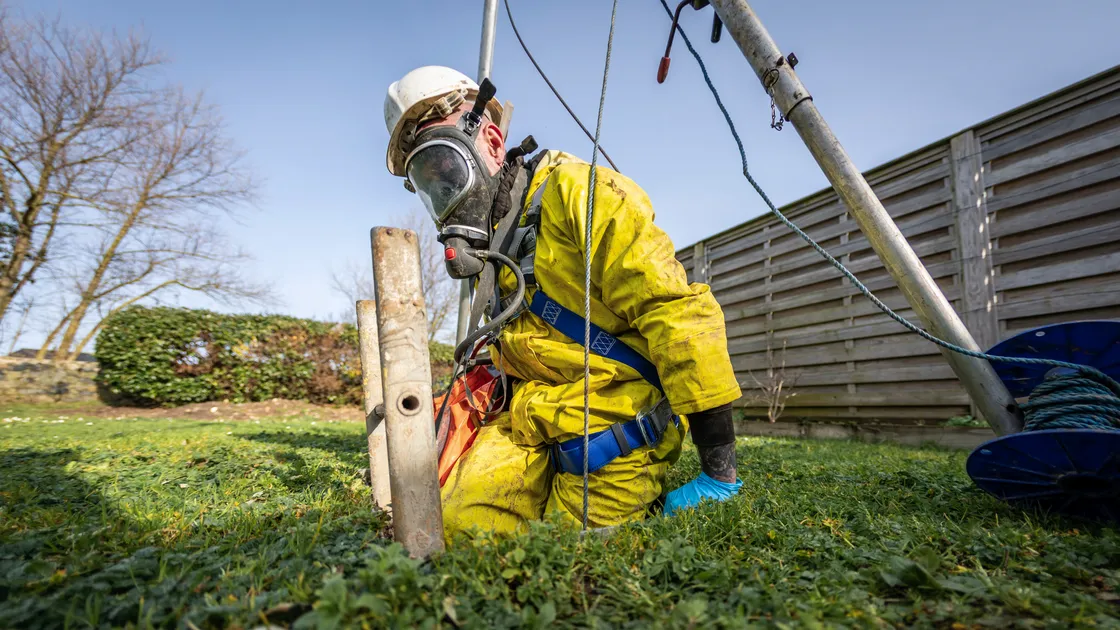 George De Carteret of Drain Away donning breathing apparatus and climbing into a cesspit to check for leaks