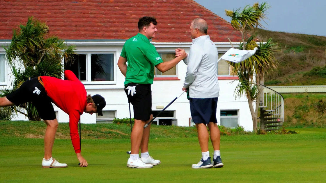 That winning feeling: Lewis Marley shakes hands with his father and caddie Mick after making a birdie two at the 18th hole at L’Ancresse yesterday to win his singles match against Jacob Townsend and seal overall victory for Guernsey in the Men’s Inter-Insular.
