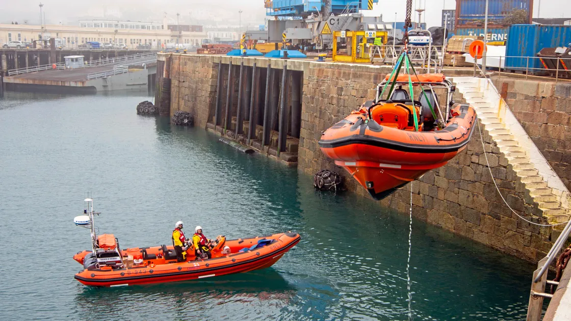 Out with the old and in with the new... The Elizabeth and Margaret Milligan inshore lifeboat is craned out of St Peter Port Harbour as coxswain Jason Norman and mechanic Stuart Carre look on from its replacement, Harold Hobbs. (Picture by Tony Rive, 33083574)