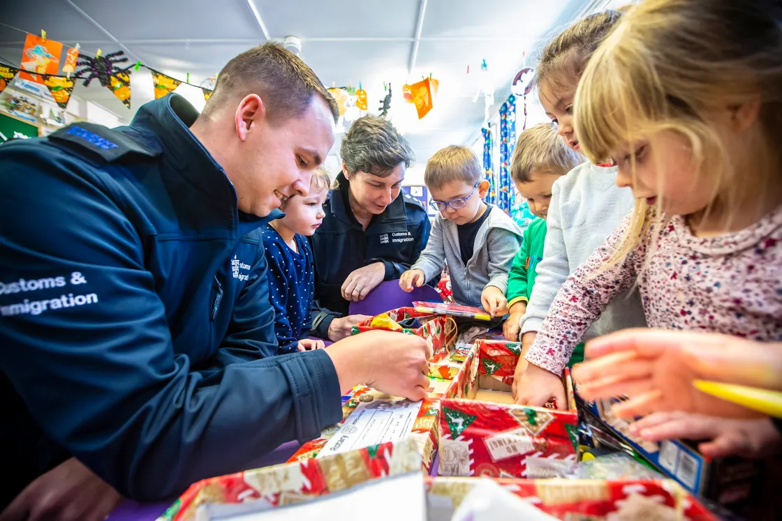 Picture by Peter Frankland. 02-11-20 Children at Little Learners Nursery have been helping to pack shoeboxes to be sent to third world countries..They have been helped by members of law enforcement, Just Games and other small businesses. Adam Le Huray and Rebecca Falla of Guernsey Border Agency help out with packing the boxes.. (28867662)