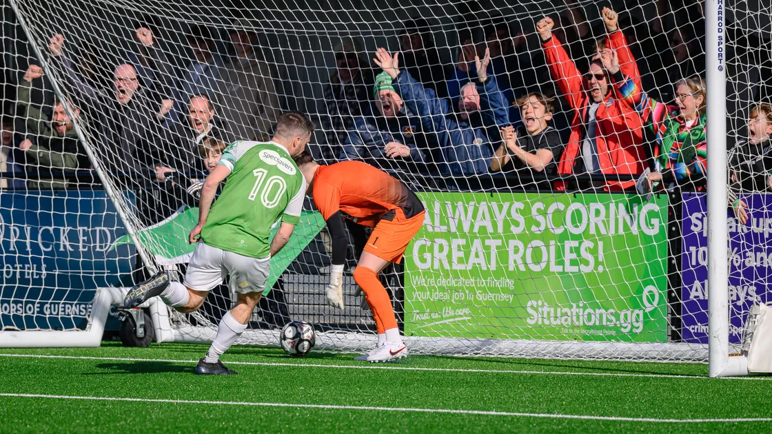 The Guernsey FC fans behind the goal at Victoria Park celebrate as Ross Allen wheels away having given his side the lead against Haywards Heath Town.