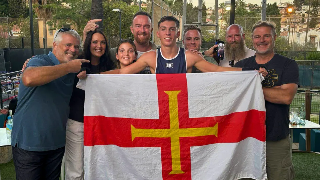 George Graham holding the Guernsey flag and surrounded by family and friends, including his dad Kevin (fourth from left) the former Guernsey Muratti defender and manager. (Picture supplied)