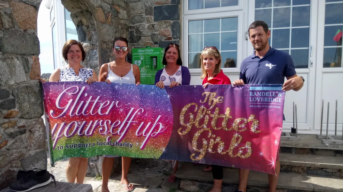 A glittering occasion on Lihou with the island now equipped with a public access defibrillator thanks to the fundraising efforts of the Glitter Girls, left to right, Nickie Browning, Sara Mallett and Natalie Gilman, at the West Show. Receiving it were the Cardiac Action Group’s Gerry Le Roy, second right, and Lihou warden Steve Sarre. (Picture by Danielle Kenneally, 28565511)
