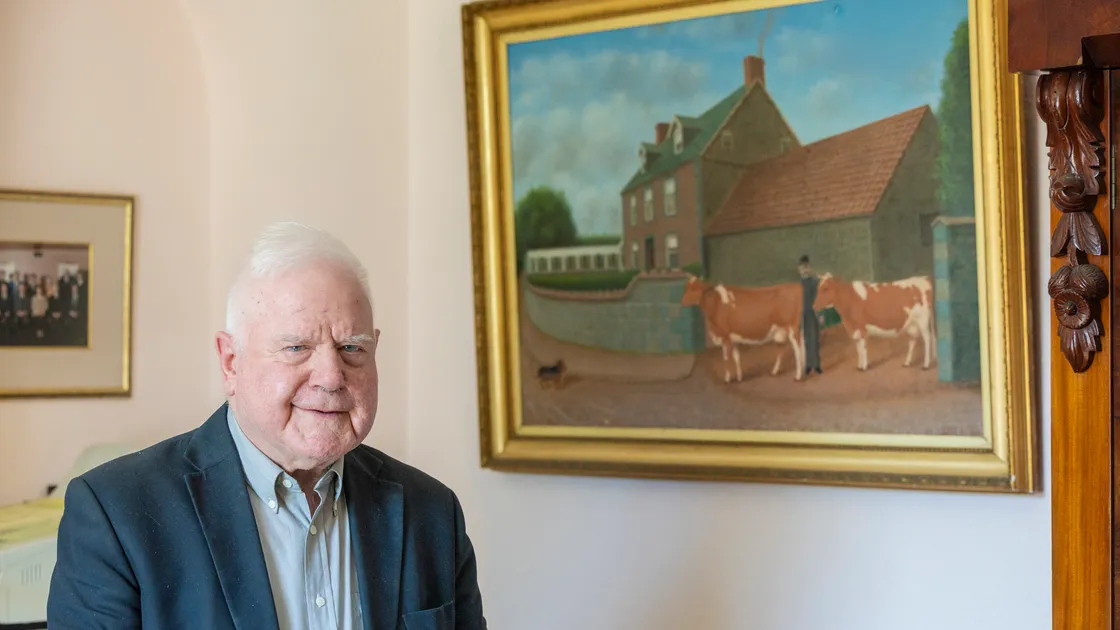 Geoff Mahy at his home in St Saviour's, beside a Corbet painting of the same farm’s exterior. 