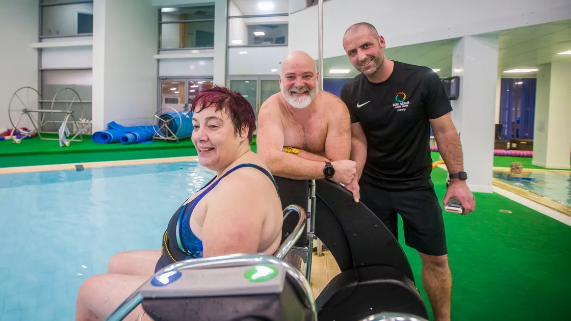 The combination of Beau Sejour duty manager Danny Le Page, right, and open water swimmer Adrian Sarchet, who is known as the Sea Donkey, conceived and raised much of the money for the PoolPod system, which allows swimmers such as Guernsey Disability Swimming member Sandra Robilliard to enter the pool in safety and with dignity. It can be used by any swimmer with mobility problems or parents with babes in arms. (Pictures by Sophie Rabey, 29113797)