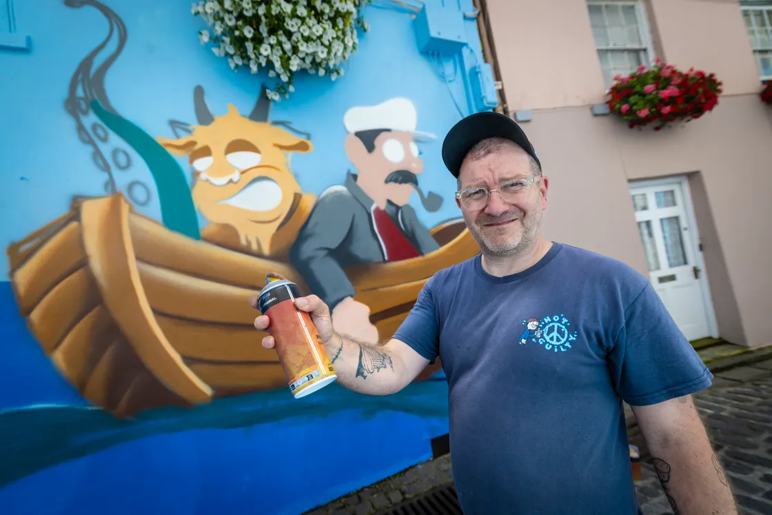 Street artist Charlie McFarley next to one of the graffiti scenes in Mansell Street.