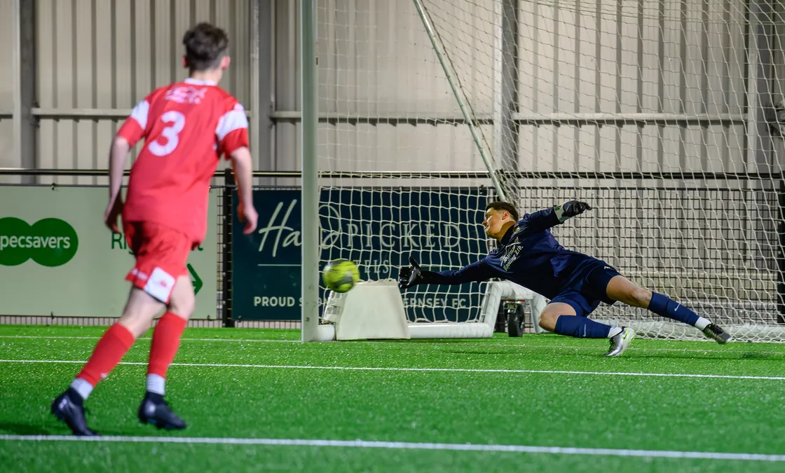 Sylvans goalkeeper Nick Batiste goes the right way but is unable to reach Louis Hunter's penalty