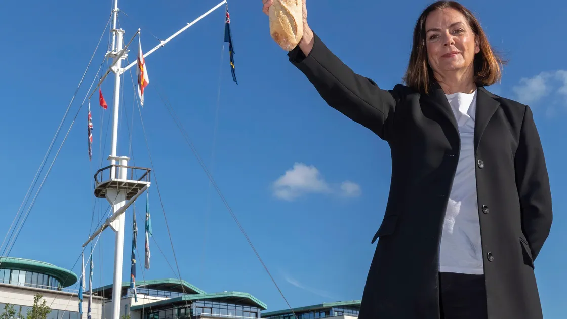 Guernsey Waste prevention and recycling officer Tina Norman-Ross holding a baguette in front of the Weighbridge mast to indicate just how much bread is being wasted in the island every day. (28569038)