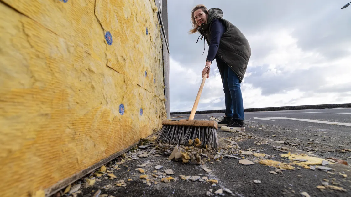 Sarah Pearl sweeping up cladding which was blown off New Image Hairdressers at the Longstore