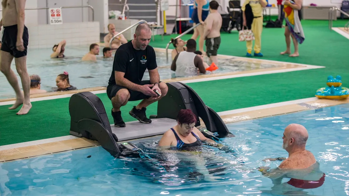 Danny Le Page, poolside, and Adrian Sarchet, in the water, watch as Guernsey Disability Swimming member Sandra Robilliard uses the PoolPod to get into the pool. (29113801)