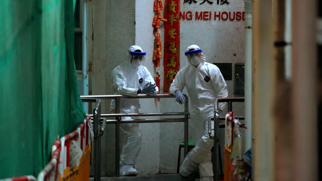 Personnels wearing protective suits wait near an entrance at the Cheung Hong Estate, a public housing estate during evacuation of residents in Hong Kong, Tuesday, Feb. 11, 2020. The Centre for Health Protection of the Department of Health evacuated some residents from the public housing estate after two cases of novel coronavirus infection to stop the potential risk of further spread of the virus. (AP Photo/Kin Cheung). (27172709)
