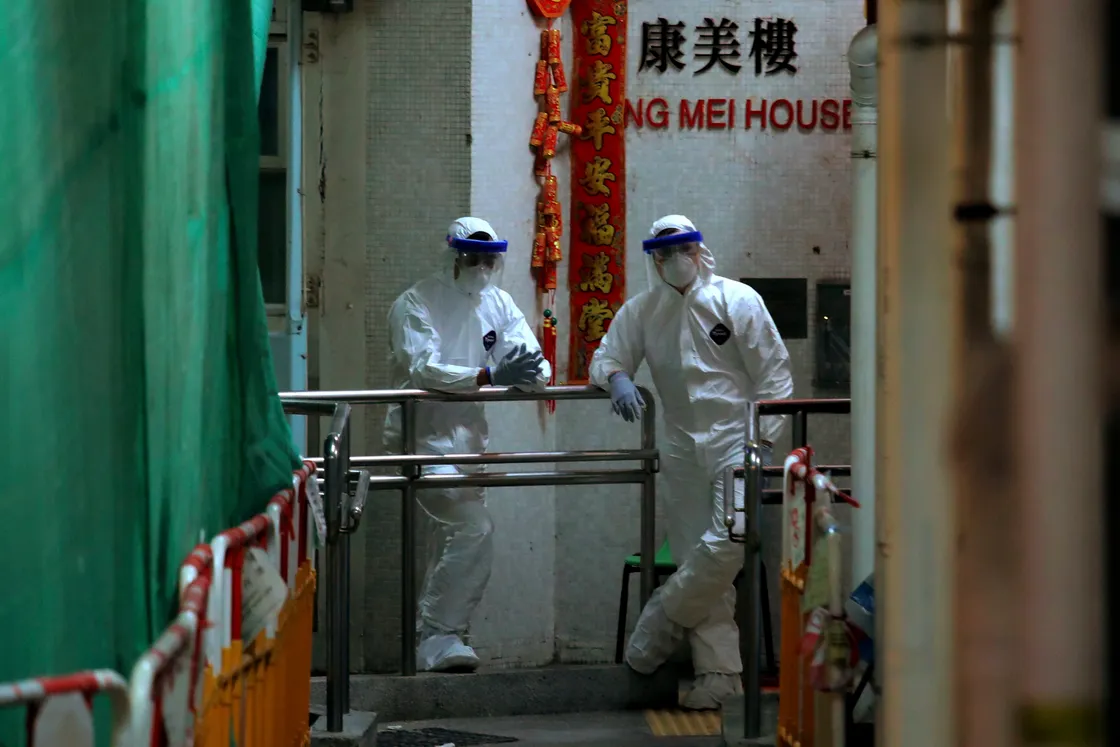 Personnels wearing protective suits wait near an entrance at the Cheung Hong Estate, a public housing estate during evacuation of residents in Hong Kong, Tuesday, Feb. 11, 2020. The Centre for Health Protection of the Department of Health evacuated some residents from the public housing estate after two cases of novel coronavirus infection to stop the potential risk of further spread of the virus. (AP Photo/Kin Cheung). (27172709)
