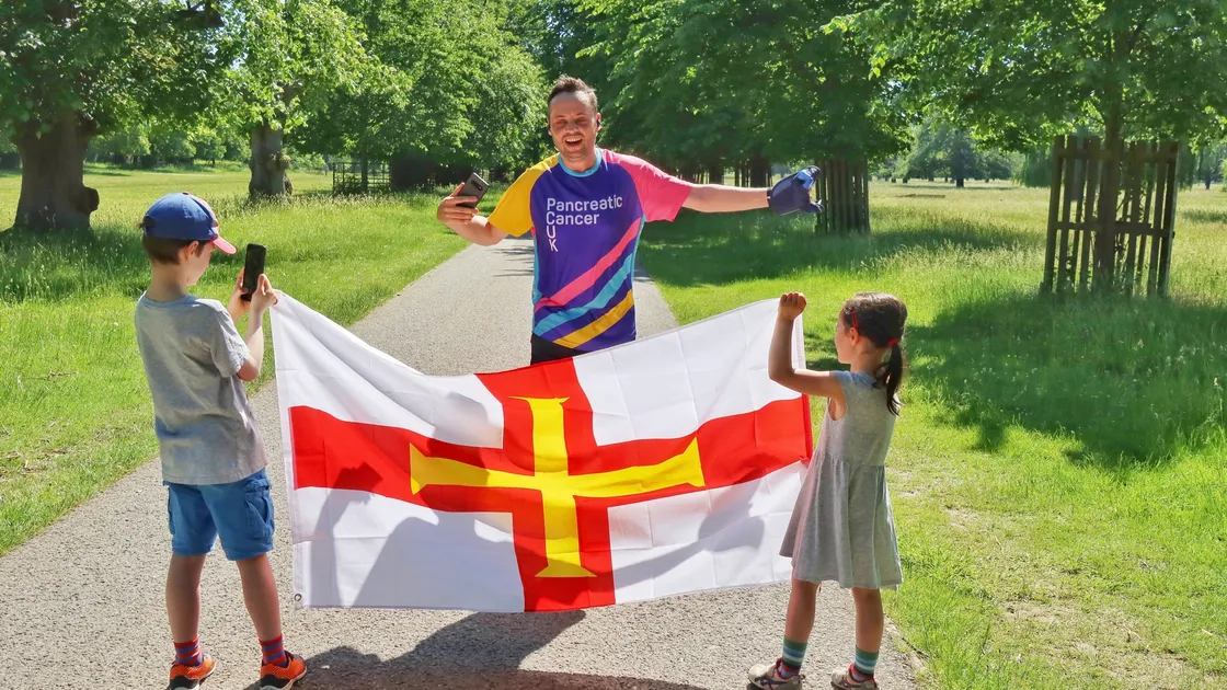 Richard Trestain's children held the Guernsey flag as finish marker in when he completed the last run in Bushy Park, near his home, to complete the 168 miles.