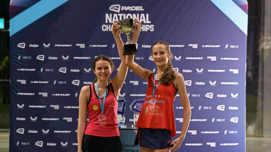 Chloe de la Mare, left, holds aloft the national U18 trophy along with her playing partner Rosie Quirk