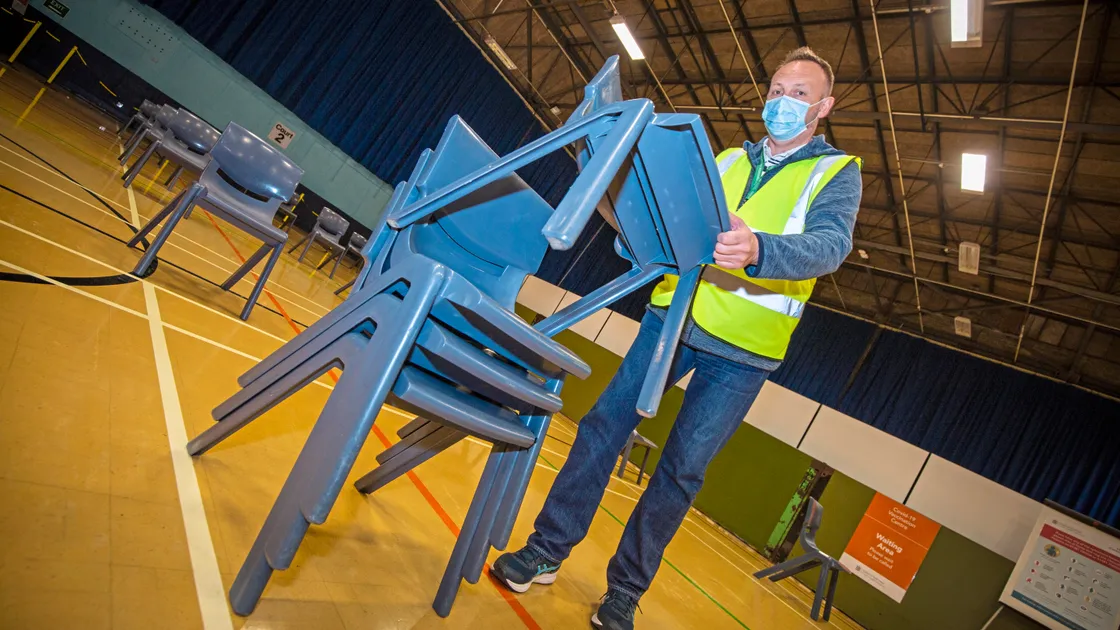 Packing up has begun at the Covid Vaccination Centre in the Sir John Loveridge Hall at Beau Sejour, which was used for the last time yesterday. Packing up the chairs as the end of the last shift is porter/safety attendant Paul Clark, a long-serving member of its staff.    (Picture by Sophie Rabey, 30636330)