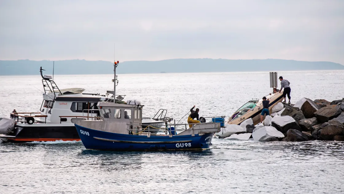 A number of vessels were used to try and pull the motorboat off the rock armour outside the QEII Marina on the high tide yesterday morning. (Picture by Sophie Rabey, 33617894)