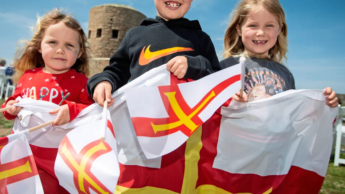 Liberation smiles and flags at Vazon from, left to right, Aoibhe, Connor and Lauren O’Neil, who were looking forward to watching the cavalcade pass. (Picture by Peter Frankland, 33217112)