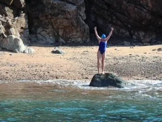 A triumphant Delphine Riley after picking up a pebble on Alderney's Trois Vaux Bay to complete her swim.