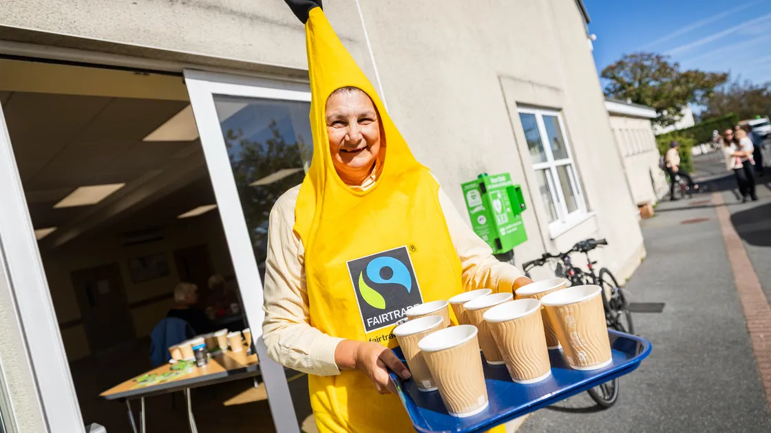 Rev Jacky Cottrell handing out hot drinks, dressed as a Fairtrade banana.