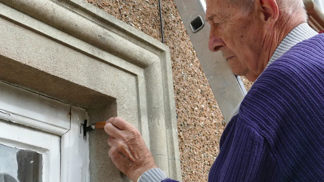 John Henry snr at his home. He shows how soft the wood is in the old windows by poking a penknife into one of the frames. (25531624)