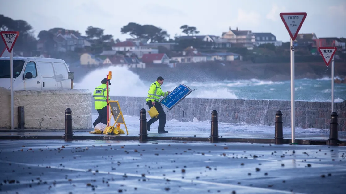 Two police officers battle the elements to put a roads closed sign in place at Cobo yesterday. (Picture by Peter Frankland, 27152931)
