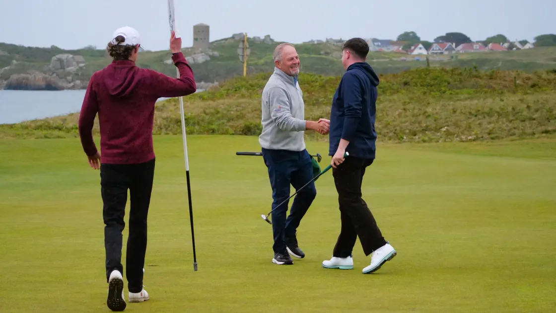 Mick Marley congratulates his son Lewis on his first-round win on the 18th green.