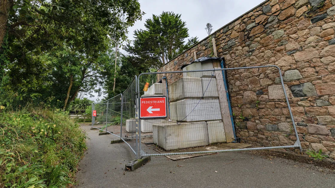 A number of large concrete blocks were placed in the road to prop up the bulging wall, closing the narrow road to cars, and have remained there ever since.