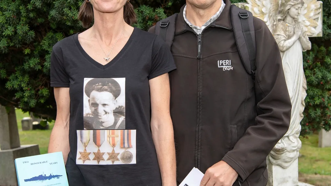 Karen Andrew, the granddaughter of stoker Fred Andrew, whose body is buried in France, attended the service wearing a shirt carrying his picture and holding a rare book about the sinking of the two ships. She was with Anthony Pearce.(Picture by Andrew Le Poidevin/TallPictures)