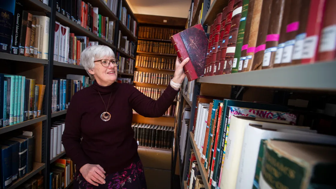 Chief librarian Sue Laker picks up just one of the more than 40,000 books in the Priaulx Library’s collection. (Picture by Peter Frankland, 31800225)