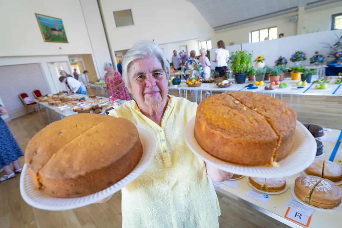 Long-serving committee member Brenda Sparkes with two of her winning cakes, one coconut and the other cherry.