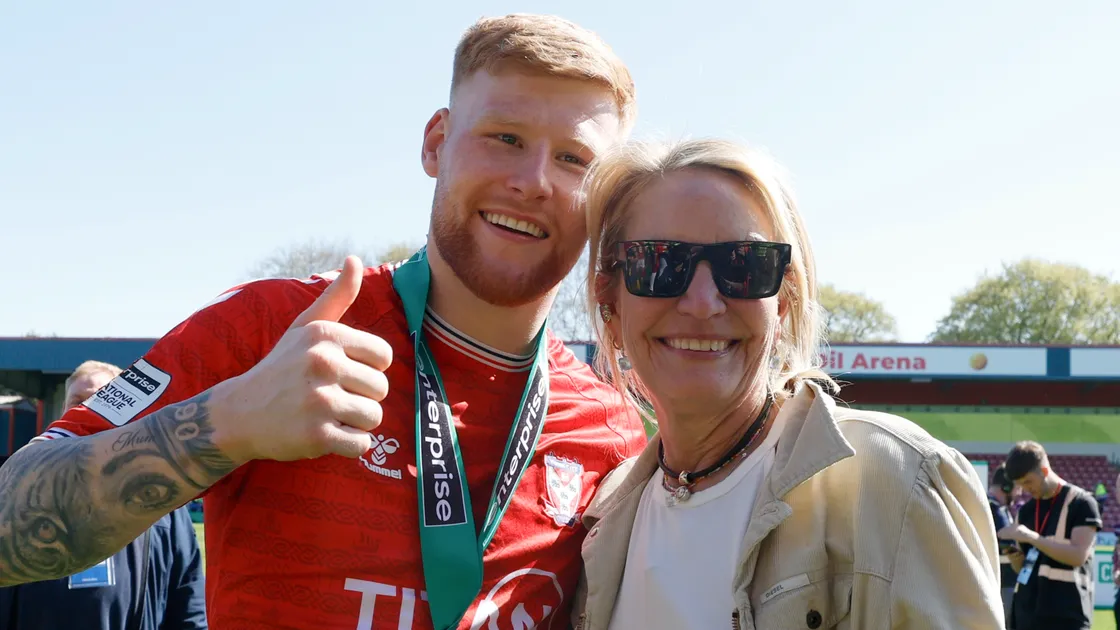 York City’s Josh Stones, left, with co-owner Julie-Anne Uggla, the woman behind the Blonde Hedgehog in Alderney, celebrate on the pitch after the Enterprise National League match at the Crown Oil Arena in Rochdale on Saturday.