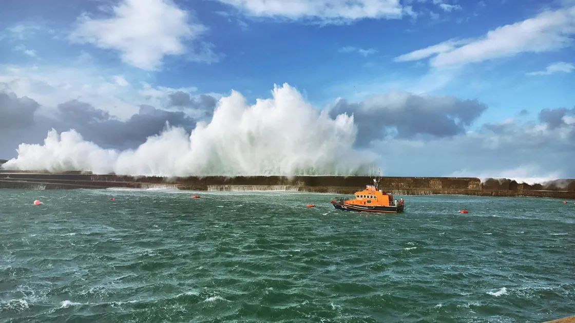 Storm waves crashing over the Alderney Breakwater with the RNLI lifeboat in the foreground. 		 (Picture by Sammy Hogg)
