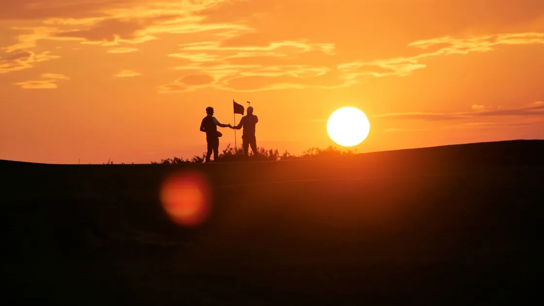 Daniel Griggs, left, and Danny Blondel shake hands on the 17th green as the sun sets. (Picture by Gareth Le Prevost, 29838778)