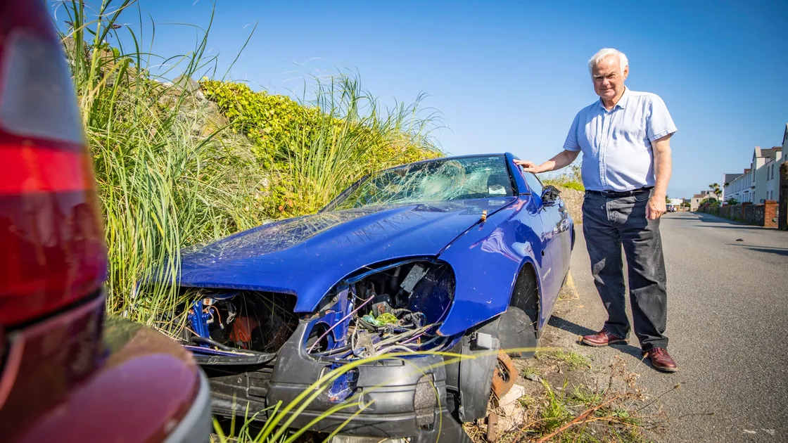 St Sampson’s parish constable Paul Le Pelley with one of the seven abandoned cars along Saltpans that have lain there for years. The parish wants the vehicles removed by their owners before 15 September. (Picture by Sophie Rabey, 29915746)