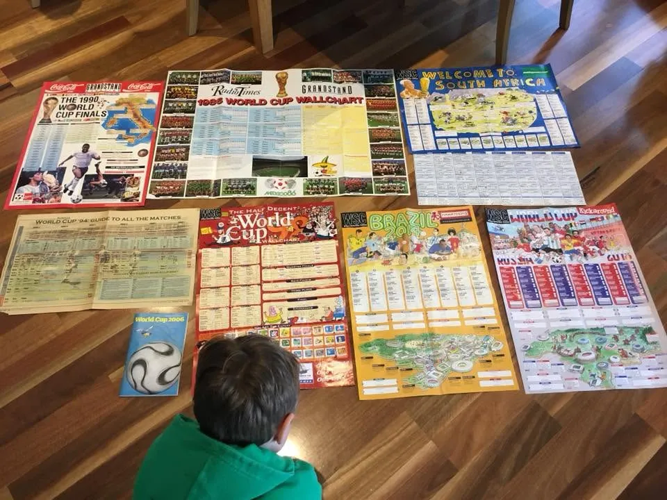 Doing his homework in 2018 – my son peruses my collection of wall-charts covering every World Cup since 1986.