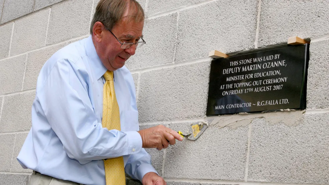 Then Education minister Deputy Martin Ozanne sets a plaque into the wall at St Sampson's High School in 2007